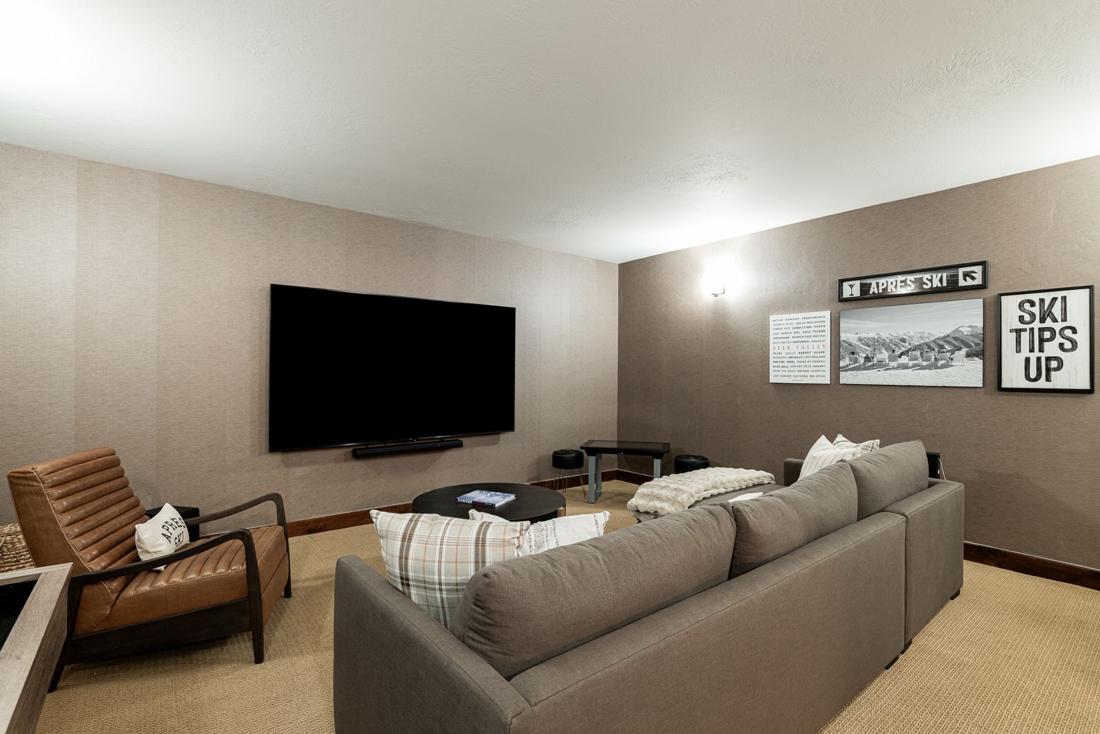 Game room media lounge with sectional sofa, large TV, and ski-themed decor at Mayflower Vista