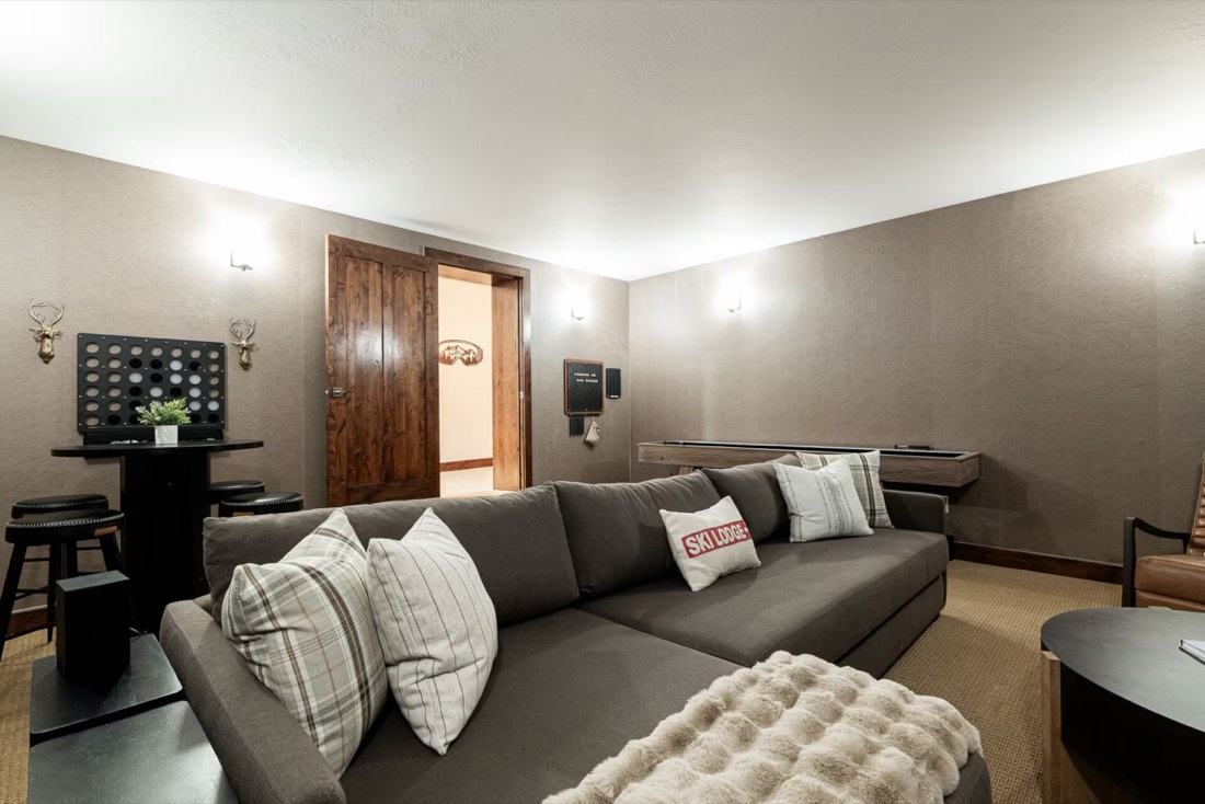Luxury entertainment game room with shuffleboard table, arcade machine, and 85-inch 4K TV
