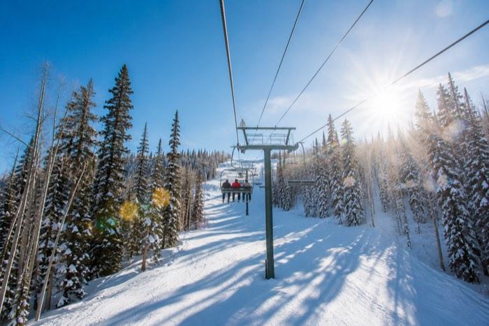 Skiers riding chairlift at Deer Valley East Village base portal near Mayflower Vista